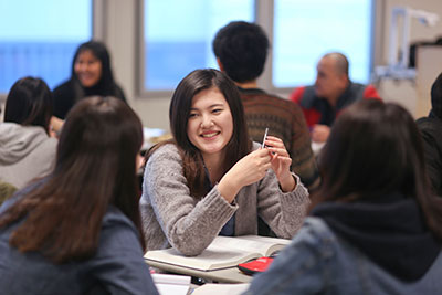 Highline College student in class holding pen and smiling