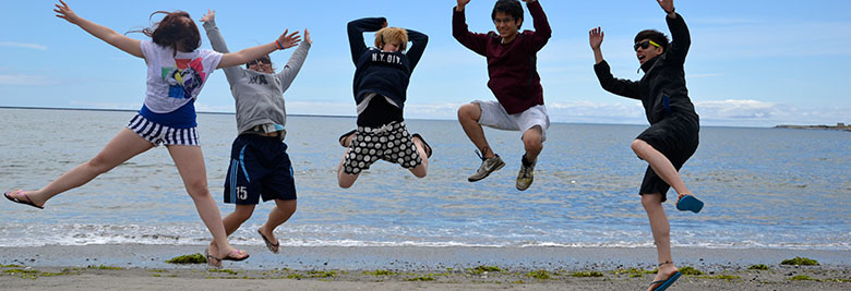 International students on a beach jumping in the air with hands waving