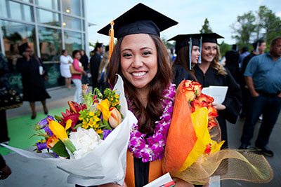 Highline College graduate at commencement with a handful of colorful flowers